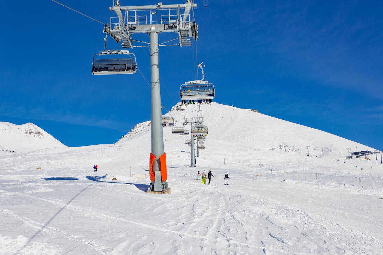 Skiers enjoy a sunny winter day at a resort in Gudauri, Georgia with scenic cable cars.